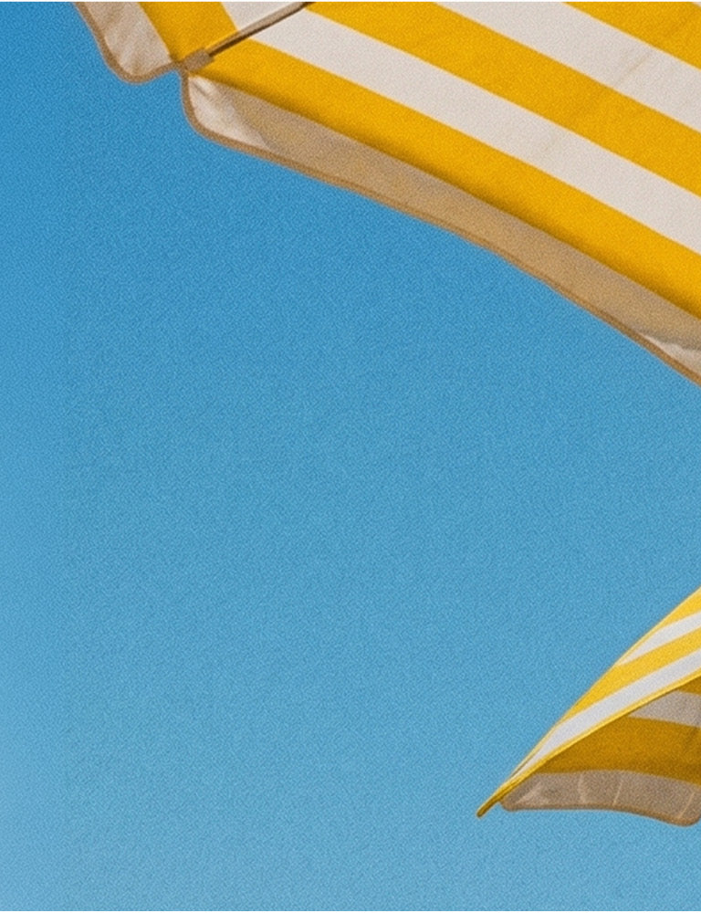 Yellow and white striped beach umbrellas against a blue sky