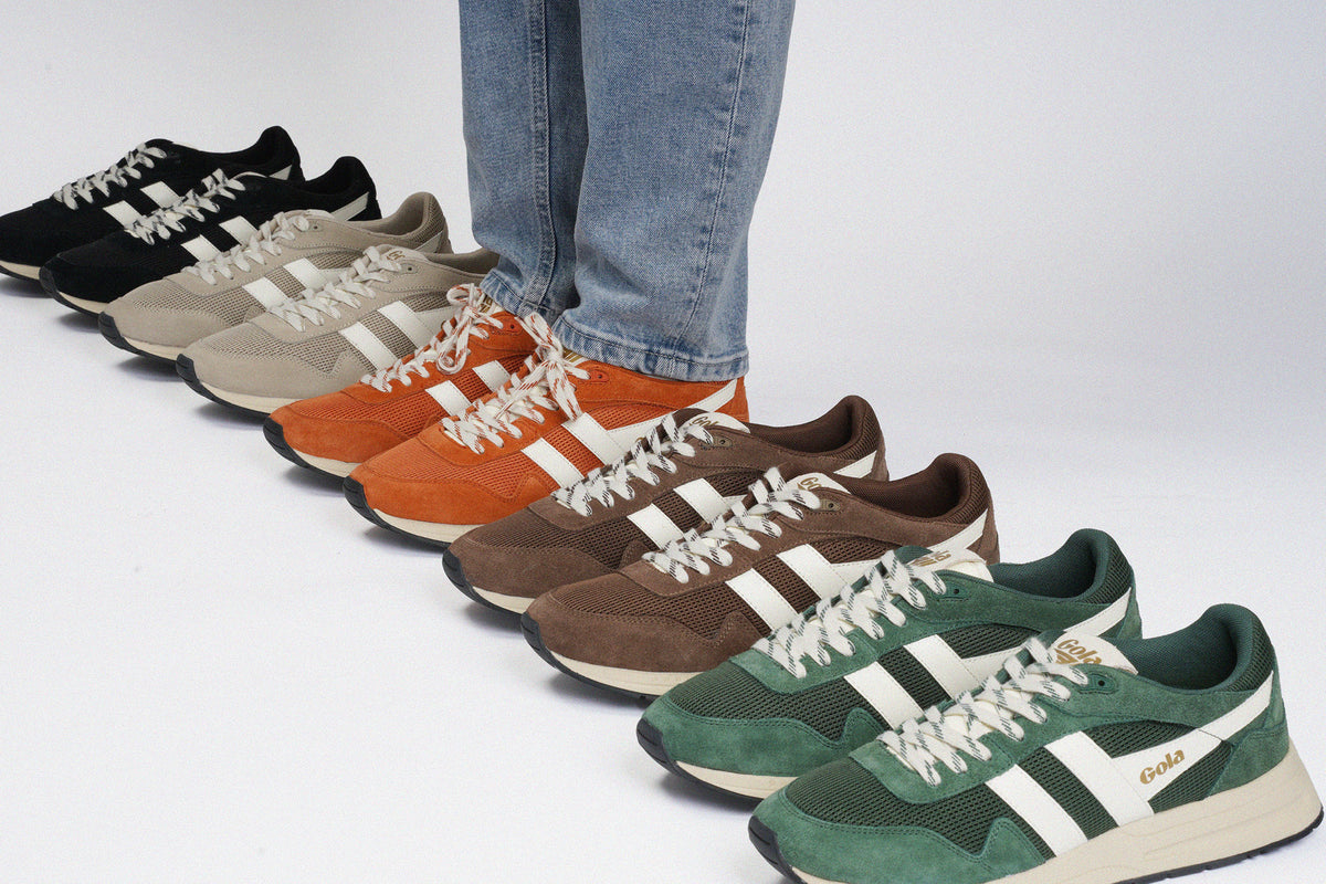 Person wearing blue jeans standing in a line of various coloured Gola trainers