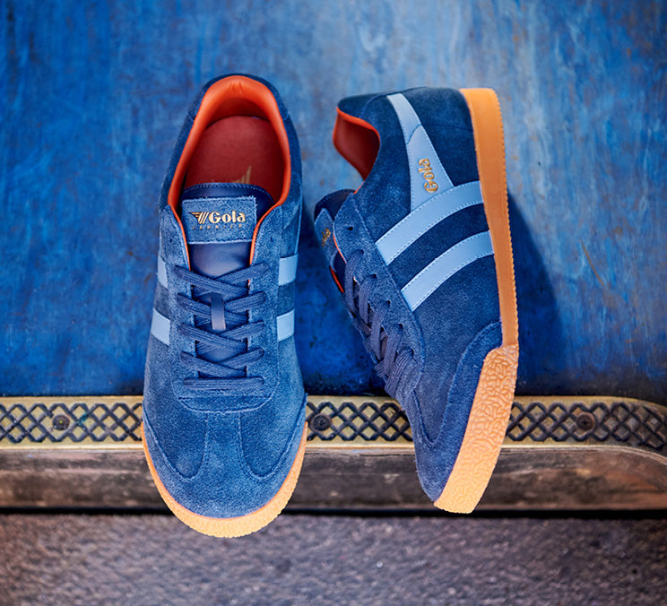 Pair of blue suede Gola sneakers with light blue stripes and orange soles.
