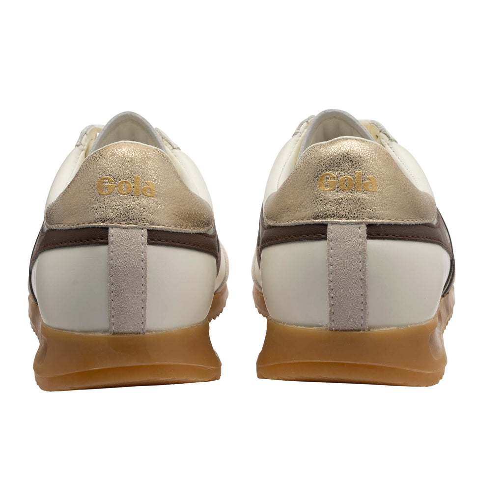 Rear view of two white and gold trainers with brown trim and gum soles