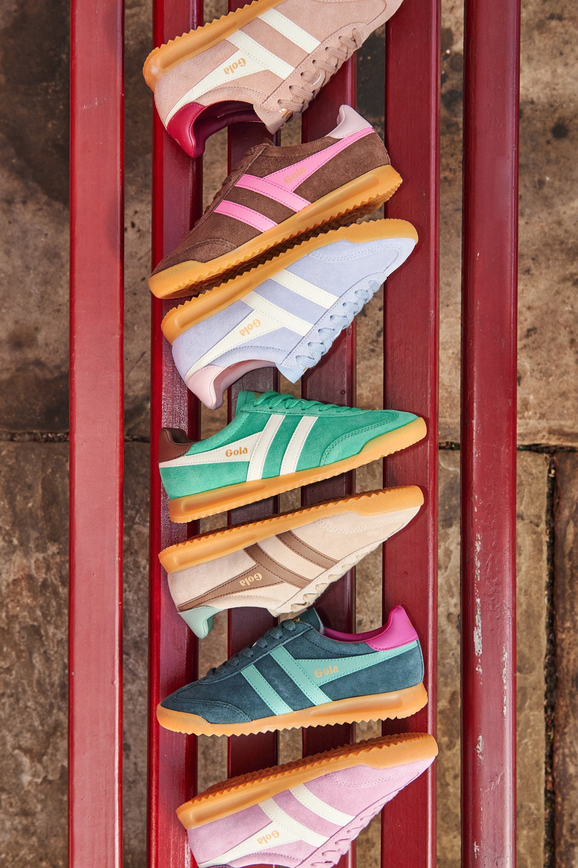 Six pairs of Gola trainers in various colours on a red slatted bench
