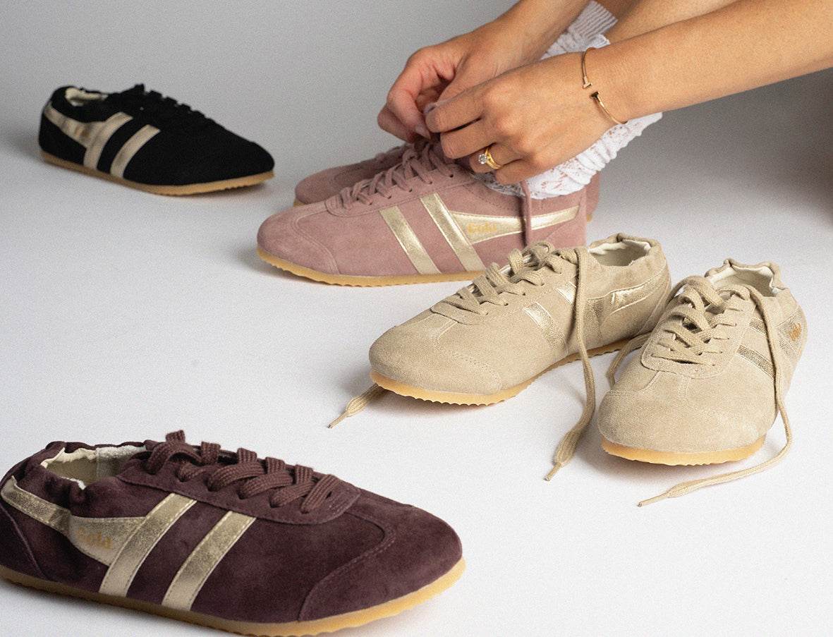 Person tying laces on Gola suede trainers in various colours on a white background