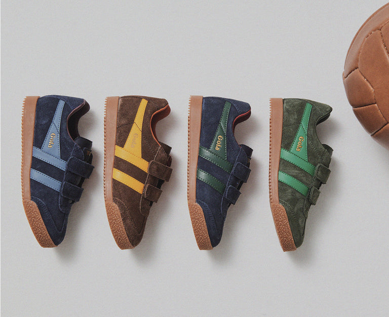 Four pairs of Gola suede trainers with hook and loop fastenings and gum soles arranged next to a leather football