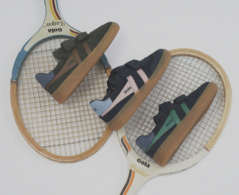 Three pairs of Gola children trainers with velcro straps arranged on vintage wooden tennis rackets