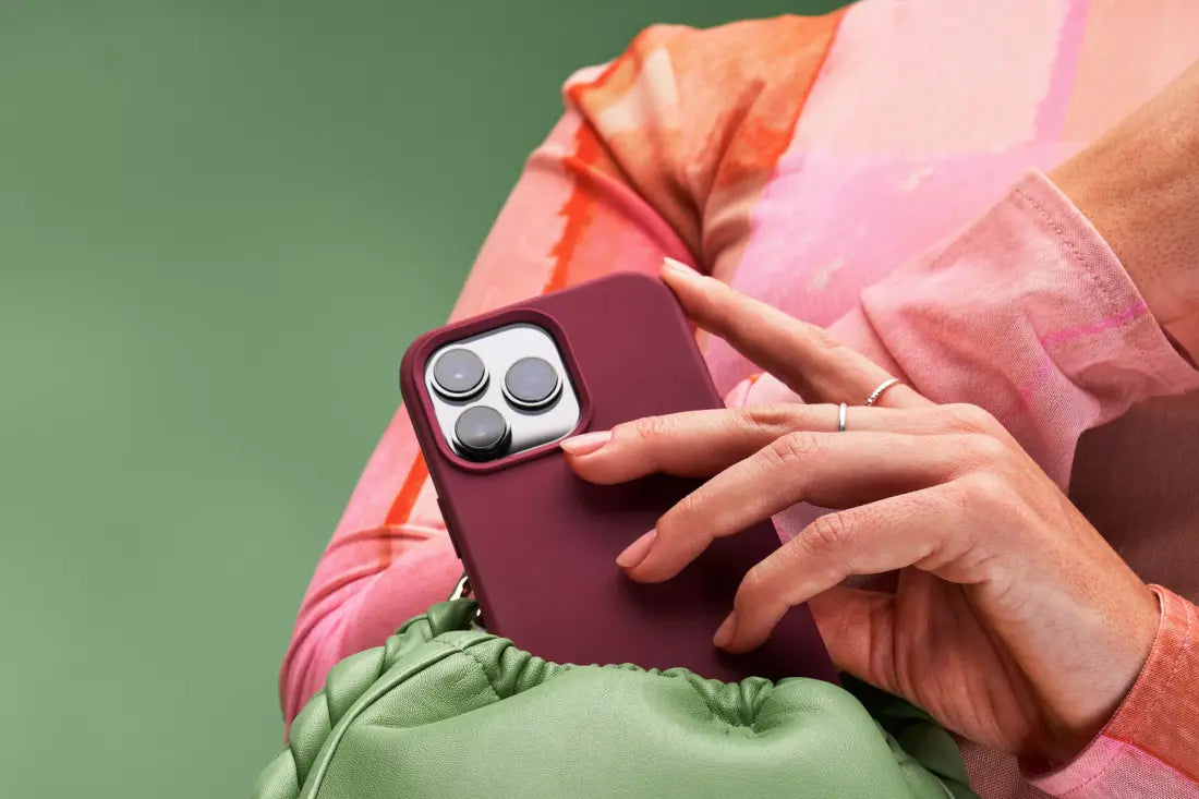A person placing a maroon iPhone into a light green purse.